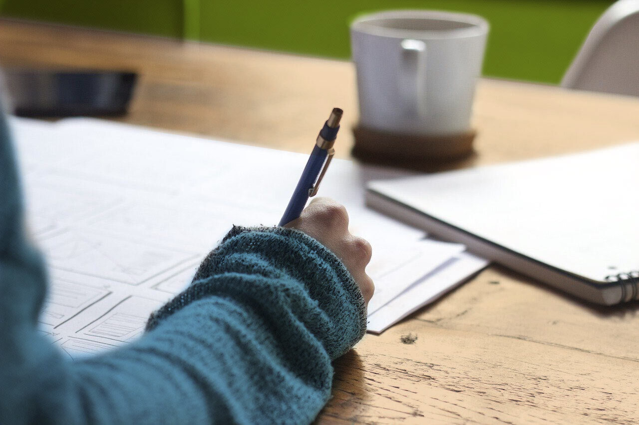 Writing on documents next to a journal on a table